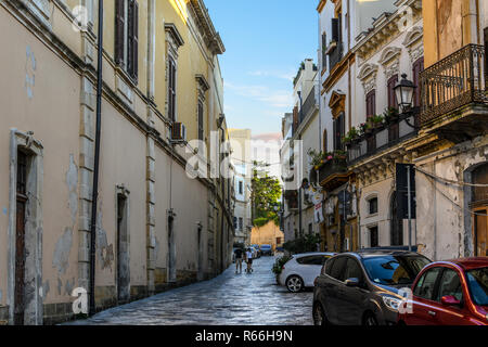 Un jeune couple pousser une poussette de bébé dans une petite allée sombre passé, des restaurants et des appartements dans le centre historique de Brindisi, Italie Banque D'Images