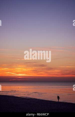 Homme seul marche sur la mer plage au coucher du soleil Banque D'Images