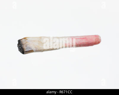 Une cigarette de cannabis aka 'Joint' qui a été fumé par une femme portant du rouge à lèvres, laissant un "Roach". Banque D'Images