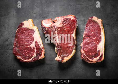 Le bœuf vieilli à sec - steaks de contre-filet, faux-filet, t-bone steaks sur noir Banque D'Images