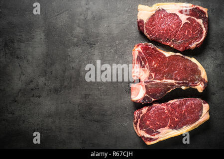 Le bœuf vieilli à sec - steaks de contre-filet, faux-filet, t-bone steaks sur noir Banque D'Images