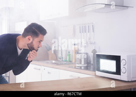 Man Spraying extincteur sur le four à micro-ondes Banque D'Images