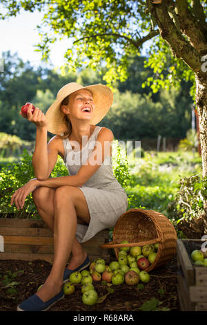 Jolie jeune femme dans son jardin jardinage - la récolte des pommes biologiques - à très heureux avec les résultats Banque D'Images