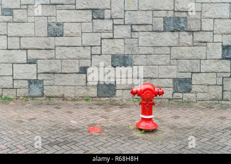 Sortie de l'eau tuyau d'incendie mur de brique rouge fond gris Banque D'Images