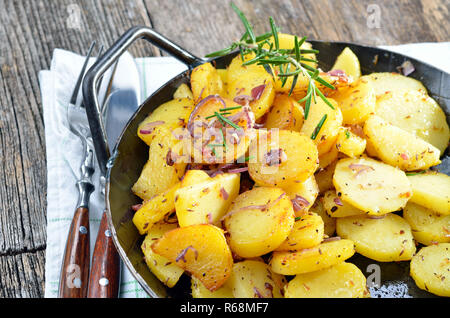 Pommes de terre sautées avec des oignons et des petits lardons dans une poêle de fer Banque D'Images