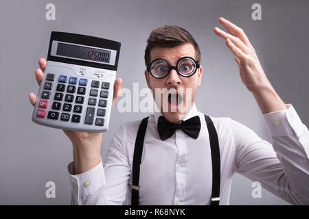 Choqué Young Man Holding Calculator Banque D'Images