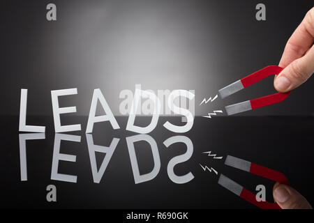 Person's Hand Holding Horseshoe aimant qui attire mène Lettre Banque D'Images