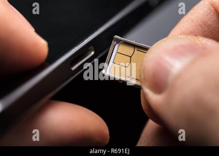 L'insertion d'une carte SIM dans un téléphone mobile Banque D'Images