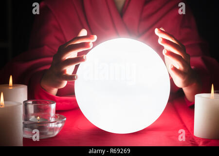 Diseuse tenir la main autour d'une boule rougeoyante Banque D'Images