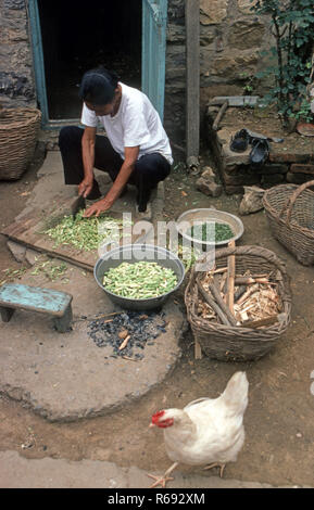 Le nord de la Chine 1980 située dans Waoning Province où une femme s'accroupit à l'extérieur de la préparation de légumes pour un repas Banque D'Images