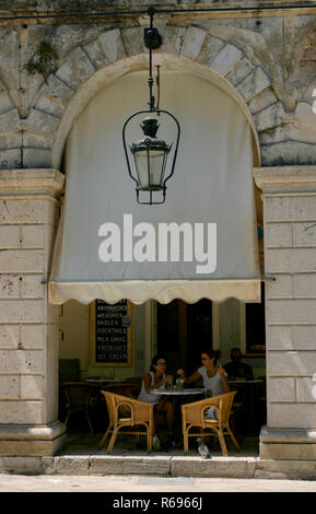 Assis à une table, dans un café,Liston, carrés, la ville de Corfou, Grèce ancienne, lampes, d'une lanterne et de voûtes en pierre.architecture d'informations. Banque D'Images