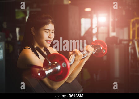 Strong young asian woman avec faisant des exercices avec haltères longs. Fitness, musculation, exercice et mode de vie sain concept. Banque D'Images