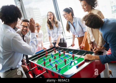 Les gens d'affaires ont beaucoup de temps ensemble.collègues playing table football in modern office Banque D'Images