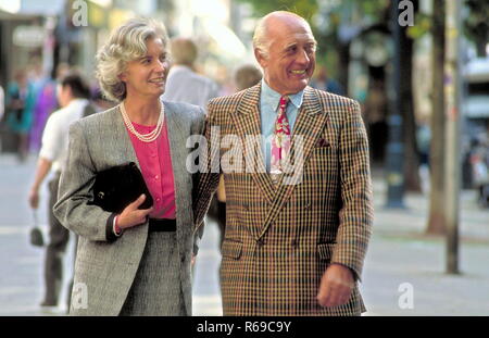 Portrait, Seniorenpaar, gepflegter Herr mit Anzug unt roter Krawatte geht mit Gattin senneur bekleidet grauen im Kostuem dans Stadt Foto Banque D'Images