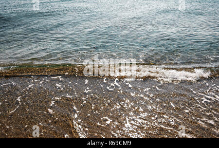 Gros plan d'une petite mer turquoise eau vague s'écraser sur le sable. Banque D'Images