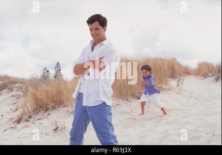 Strandszene, Ganzfigur, Mann, Mitte 30, mit weissem Hemd Jeans und mit seinem 4 tobt ausgelassen jaehrigem-Sohn dans 'The Fashion den Duenen Banque D'Images