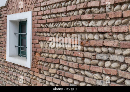 Vue oblique d'un mur de briques et blocs avec une fenêtre verte Banque D'Images