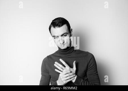 Close up portrait noir et blanc d'un jeune homme portant un cavalier, à col roulé sur le côté, contre un arrière-plan studio Banque D'Images