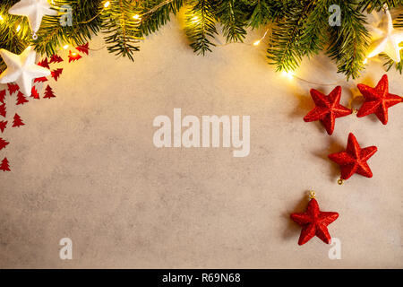 Fond de Noël avec des lumières, sapin, blanc et rouge brillant étoile sur table béton gris. Vue de dessus avec l'exemplaire de l'espace. Banque D'Images