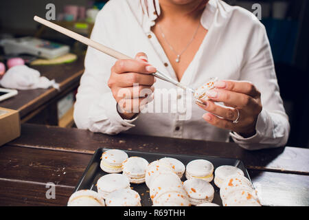 Processus permettant de macarons. L'accent peu profondes avec pinceau peinture alimentaire. Banque D'Images