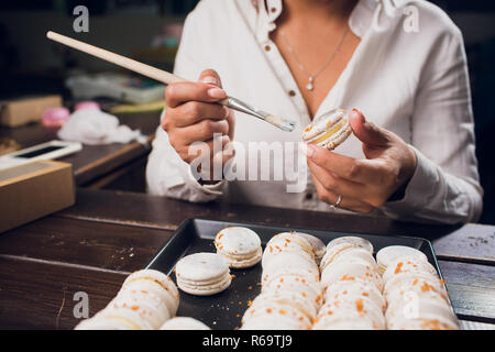 Processus permettant de macarons. L'accent peu profondes avec pinceau peinture alimentaire. Banque D'Images