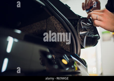 Les mains des travailleurs installe le film protecteur de peinture voiture d'enrubannage. Banque D'Images