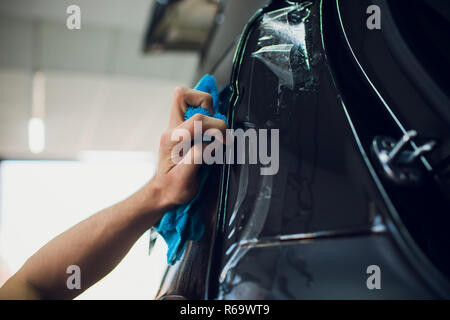 Les mains des travailleurs installe le film protecteur de peinture voiture d'enrubannage. Banque D'Images