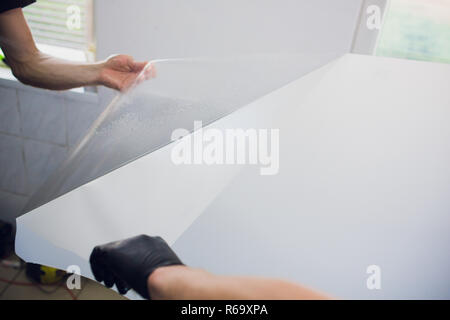 Les mains des travailleurs installe le film protecteur de peinture voiture d'enrubannage. Banque D'Images