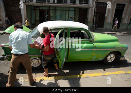 Les hommes cubains le chargement d'un vieille voiture américaine des années 50 avec des canettes dans les petites rues de Cienfuegos Cuba Banque D'Images