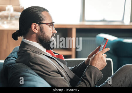 Businessman wearing glasses contrôle prévisions météo sur son téléphone Banque D'Images