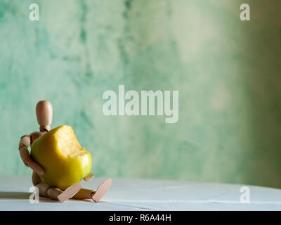 Une figurine en bois avec un mordu de green apple sur une table Banque D'Images