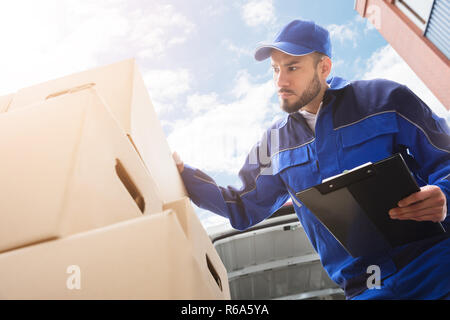 Travailleur homme debout près de boîte en carton Holding Clipboard Banque D'Images