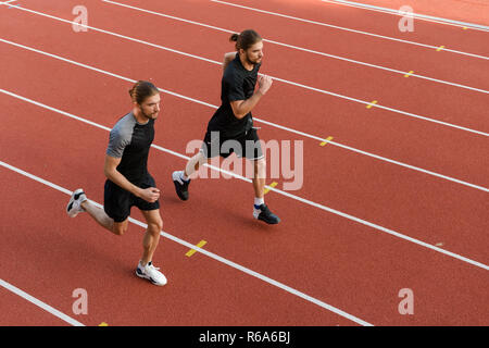 Image des jeunes deux frères jumeaux sportifs fonctionnant à l'extérieur du stade. Banque D'Images