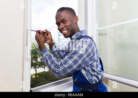 Homme en uniforme fixant la fenêtre en verre Banque D'Images
