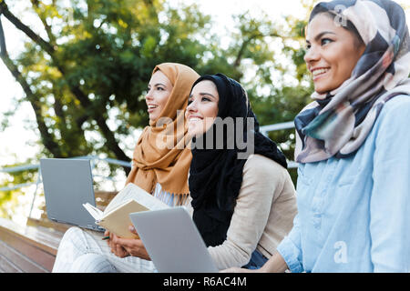 Photo de jeunes filles musulmanes portant des headscarfs au repos dans Green Park et de l'étude sur l'ordinateur portable Banque D'Images