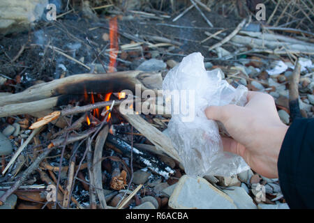 Sac en plastique dans la main de l'homme près de feu. Concept de l'incinération des déchets. La pollution de l'air Banque D'Images