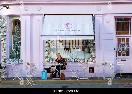 Londres, Royaume-Uni - 30 NOVEMBRE 2017 : jeune femme est assis à l'extérieur à la mode cake shop dans l'élégant salon de Chelsea. Banque D'Images