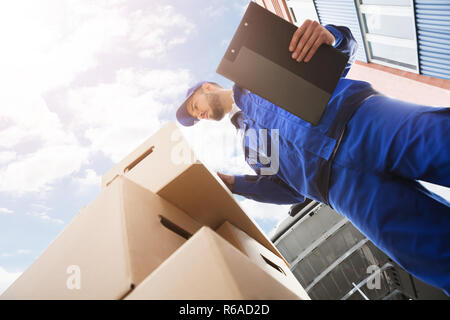 Travailleur homme debout près de boîte en carton Holding Clipboard Banque D'Images