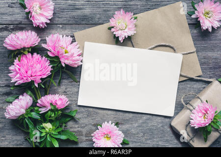 Carte de souhaits avec blanche aster rose fleurs, bourgeons et boîte-cadeau sur fond de bois rustique. Télévision. maquette. vue d'en haut. La tonalité vintage Banque D'Images