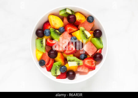 Bol de salade de fruits frais et sain sur fond de marbre blanc. alimentation saine. vue d'en haut. Banque D'Images