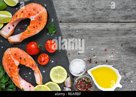 Darnes de saumon cru frais avec des épices, des herbes, des tomates et citron sur ardoise noire. Régime alimentaire sain et l'alimentation. concept de cuisine. Vue de dessus with copy space Banque D'Images