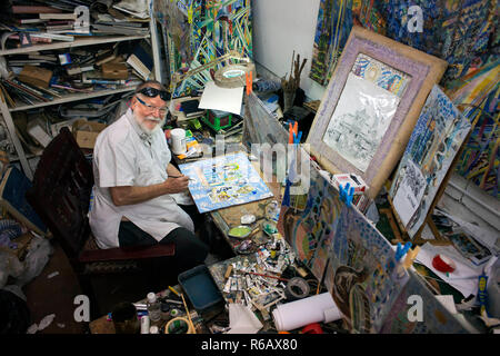 Michael Adams peintre assis dans son studio à Anse Poules bleues, l'île de Mahé, Seychelles. Baie Lazare, Anse aux poules bleues, l'artiste Michael Adams Banque D'Images