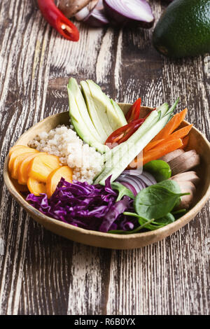 Bol déjeuner végétalien avec le quinoa, les fruits et légumes frais, d'avocat, les épinards, le chou rouge, les champignons, l'oignon rouge, carotte et citron vert, table rustique, fermer Banque D'Images