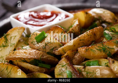 Quartiers de pommes de terre au four avec la ciboulette, l'aneth et sauce tomate. Végétarien végétalien légumes bio faits maison les quartiers de pommes de terre les grignotines. Banque D'Images