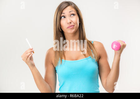 Belle Jeune femme tenant cigarette dans une main et l'haltère dans Second Hand et la pensée. Banque D'Images