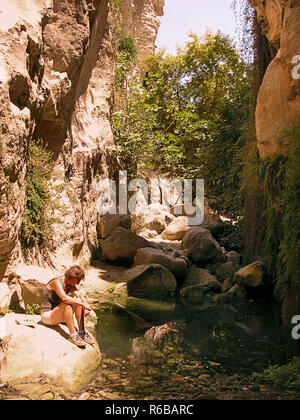 Avakas (AVGAS) Gorge, district de Paphos, Chypre : ravin avec piscine et female hiker reposant sur un rocher. Parution du modèle Banque D'Images