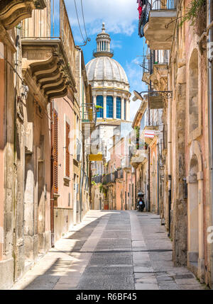 Un étroit et pittoresque route dans Ragusa Ibla avec le dôme de Saint George Duomo. La Sicile, le sud de l'Italie. Banque D'Images