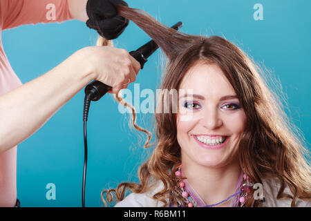 Curling coiffure femme cheveux avec le fer à friser électriques tong. Fille de coiffeur coiffure. Jolie jolie jeune femme. La beauté. Banque D'Images