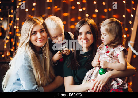 Deux mères assis avec mignon enfants cadeaux de Noël. Banque D'Images