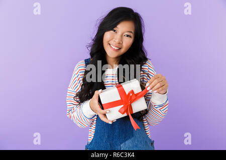 Image de jeune asiatique excité belle attractive woman posing holding gift box intérieur isolé. Banque D'Images